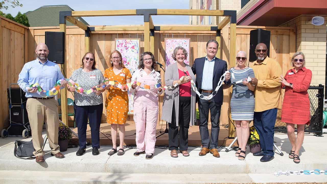 Photo of Board members, staff, and state legislators hold the student-made paper chain for the ribbon cutting at Red Caboose’s grand opening on September 30, 2023.