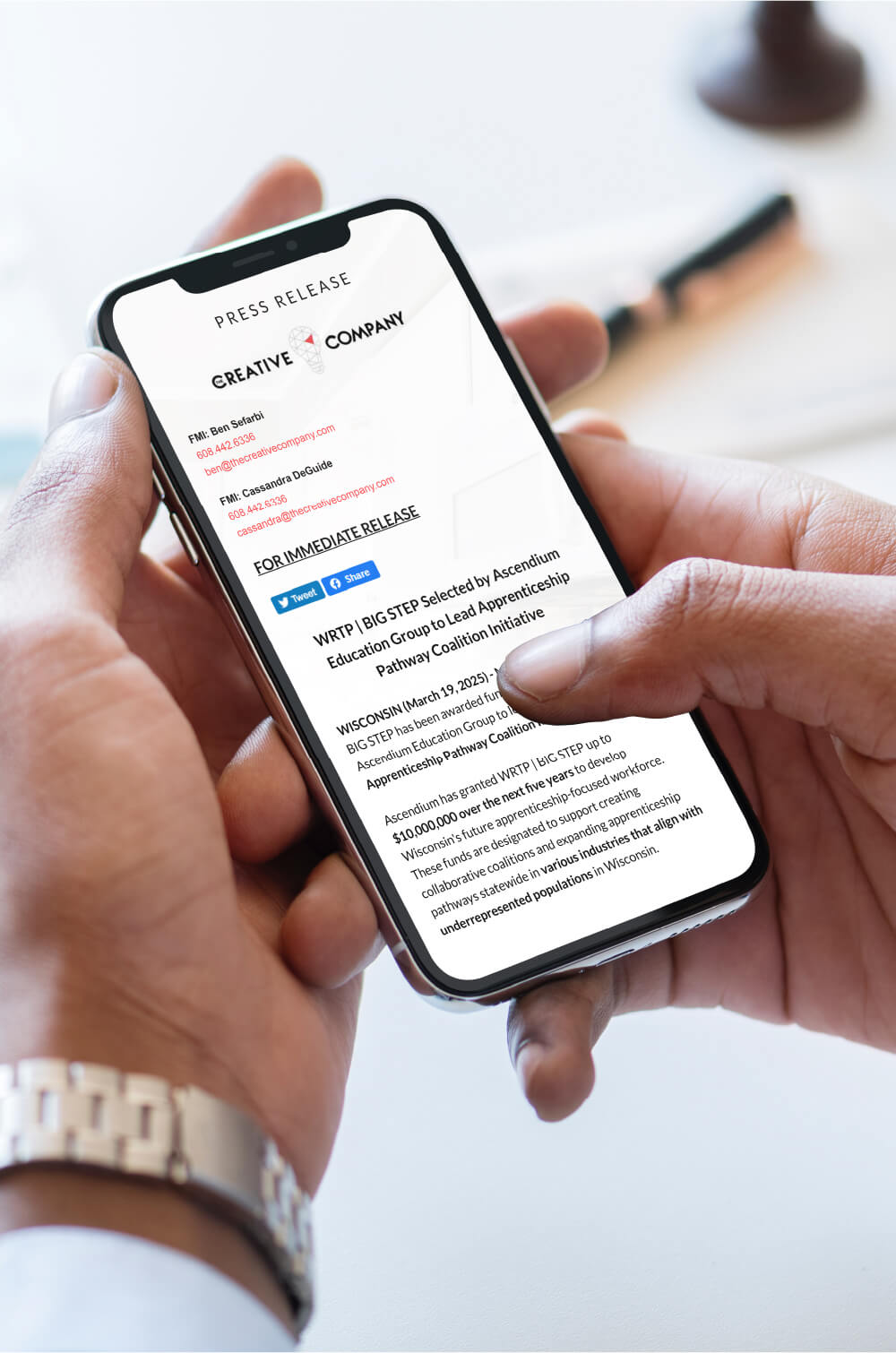 Hands holding a phone displaying a press release for Ascendium Education Group.