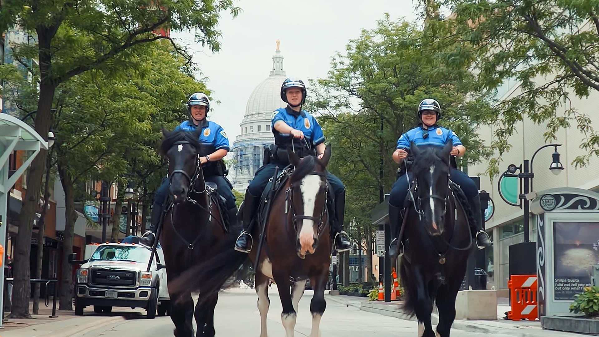Madison Police Department mounted officers ride down State Street with the Wisconsin State Capitol in the background as part of a video recruitment campaign in Madison, WI.