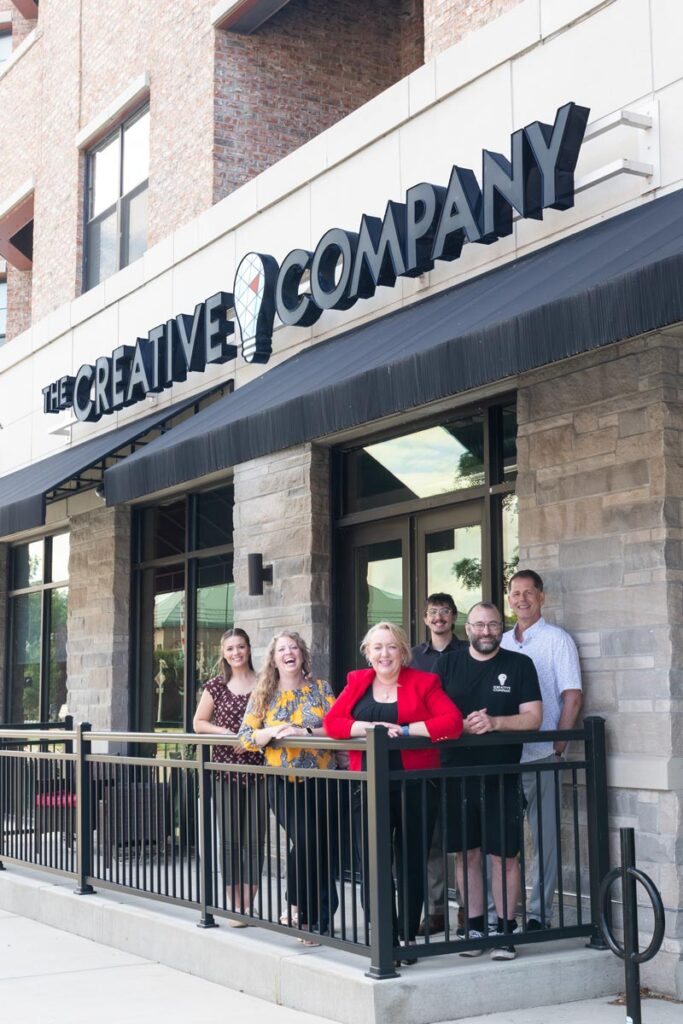 The Creative Company team, August 2025, standing on the porch in front of their office on West Washington Avenue in downtown Madison, Wisconsin.